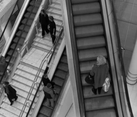 Keegi teadis, kuhu minna soovin, enne kui sellest ise teadlikuks sain. Mustvalge foto kaubanduskeskuse eskalatoritest, inimesed liiguvad treppidel eri suundades.