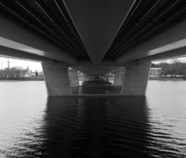 Vaade Pärnu kaarsilla alt - valguse ja varju liikumine üle jõepeegli. Mustvalge foto Pärnu kaarsilla alt, vaade sillatugedele ja jõele.