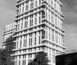 Mustvalge foto modernsest hoonest. Astmelise arhitektuuriga kõrghoone tõuseb linna kohal, rõhutades vertikaalsust ja kaasaegset linnaruumi. Mustvalge foto modernsest kõrghoonest astmelise arhitektuuri ja valge fassaadiga